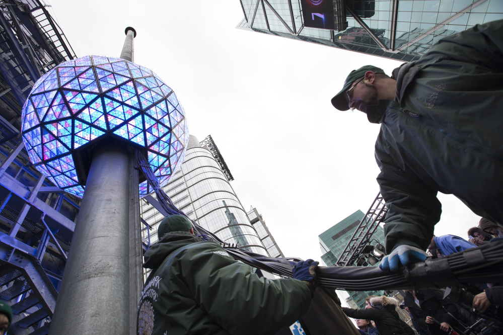Workers handle cables attached to the New Year’s Eve ball during a test atop the 1 Times Square building, Monday, Dec. 30, 2013, in New York. The iconic 11,875-pound geodesic sphere covered in 2,688 Waterford Crystal triangles will descend a 130-foot pole to mark the stroke of midnight during the annual Times Square celebration.