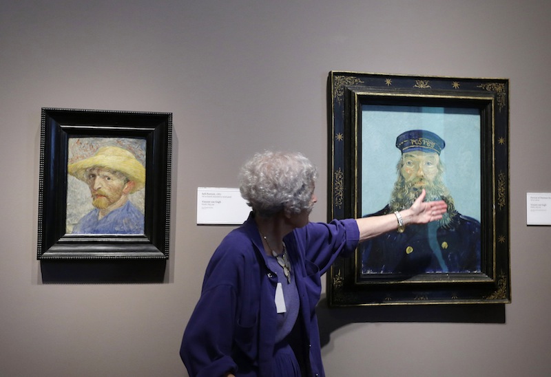In a June 13, 2013 file photo, Detroit Institute of Arts docent Lea Schelke points out details in the Portrait of Postman Roulin by Van Gogh displayed at the museum in Detroit. A closer look at the DIA art collection now being appraised by Christie’s. It’s report to state-appointed emergency manager Kevyn Orr could come out by mid-December. It’s looking more and more like that’s what debtors want to go after.