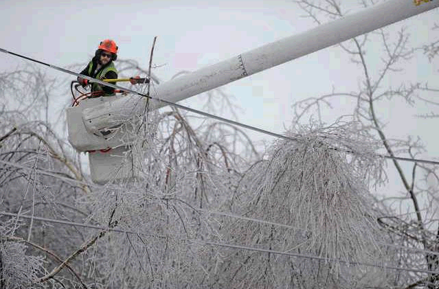 Andrew Powers, an arborist with Asplundh Tree Experts, clears power lines from iced-over branches along Mayflower Heights Drive in Waterville on Monday.