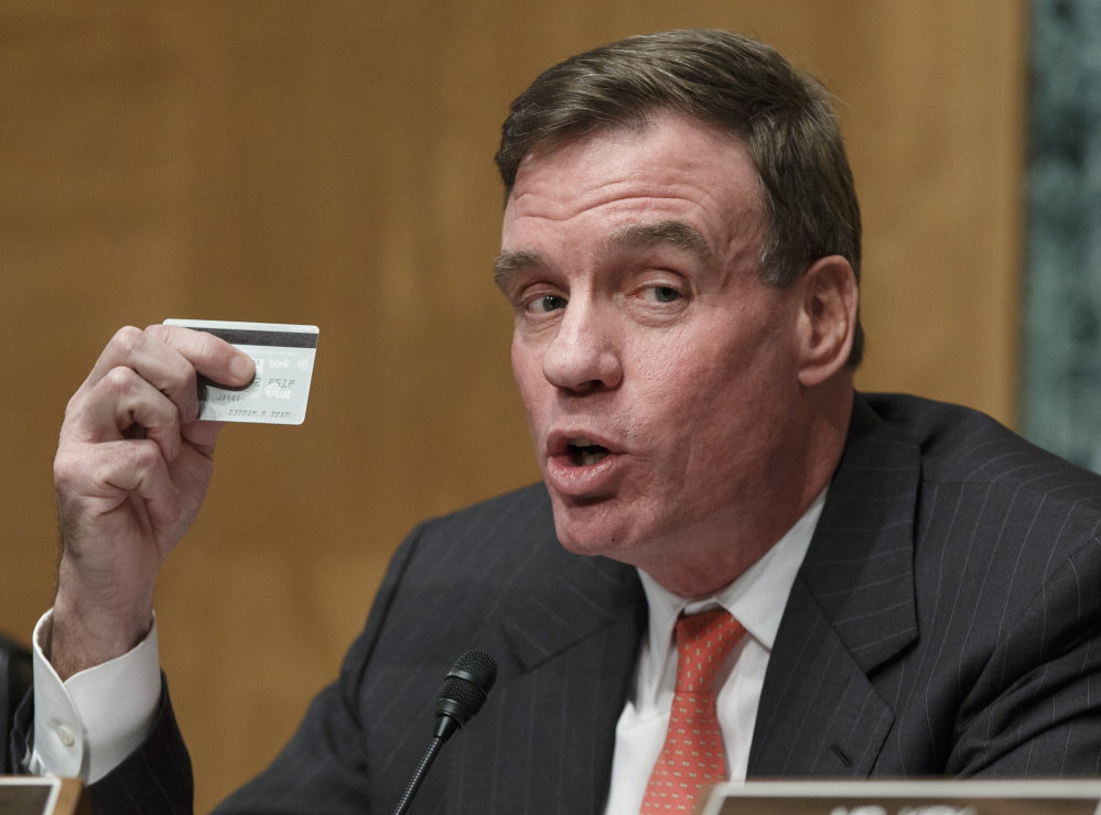 Sen. Mark Warner, D-Va., chairman of the Senate Banking Subcommittee on National Security and International Trade and Finance, displays his personal bank card as he leads a hearing on the recent incidents of mass credit card fraud following the theft of consumers’ data at retailers such as Target Corp and Neiman Marcus during the holiday shopping season, on Capitol Hill in Washington, Monday, Feb. 3, 2014. Hackers stole about 40 million debit and credit card numbers and also took personal information. (AP Photo/J. Scott Applewhite)