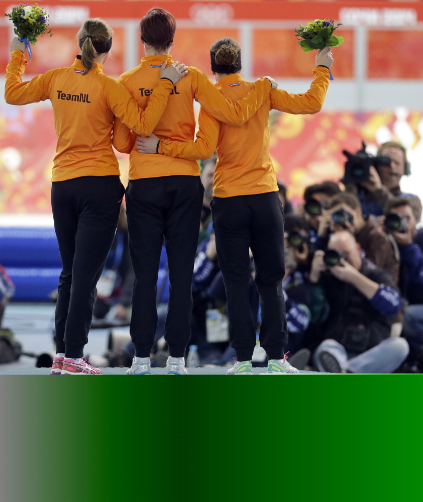 Athletes from the Netherlands, from right to left, silver medalist Ireen Wust, gold medalist Jorien ter Mors and bronze medalist Lotte van Beek celebrate during the flower ceremony for the women’s 1,500-meter speedskating race at the Adler Arena Skating Center during the 2014 Winter Olympics in Sochi.