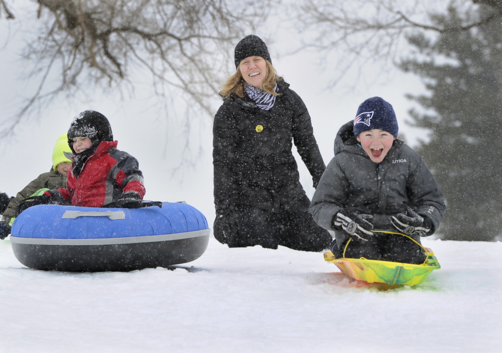 Paula Blake of Falmouth pushes her son Ethan Doucette, 6, right, down a steep slope at Maine Audubon in Falmouth as friends Noah Herdrich, 7, and Cayden Jaynes, 6, left, also of Falmouth, join in Tuesday at the start of the latest snowstorm to hit southern Maine.