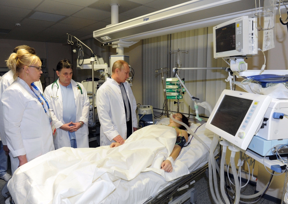 In this photo provided by RIA Novosti Kremlin, Russian President Vladimir Putin, center, speaks to skier Maria Komissarova in a hospital in Krasnaya Polyana, Russia, on Saturday, Feb. 15, 2014. The 23-year-old Russian ski cross racer fractured her spine during a training session Saturday and underwent a 6 hour surgery.