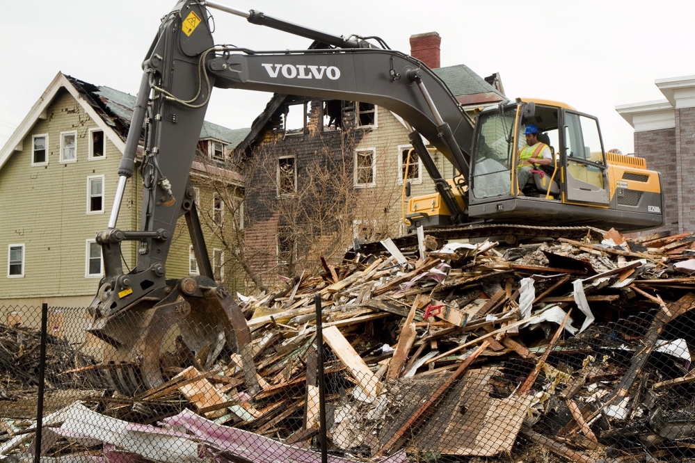 A demolition crew member cleans up the rubble from the Blake Street fire in Lewiston in May.