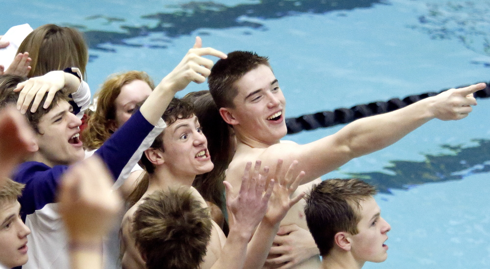 Julian Abaldo, Mark McCluskey and Kyle Crans of Camden Hills react to a time by one of their teammates during the Class B boys’ swimming meet Tuesday at Bowdoin College in Brunswick.