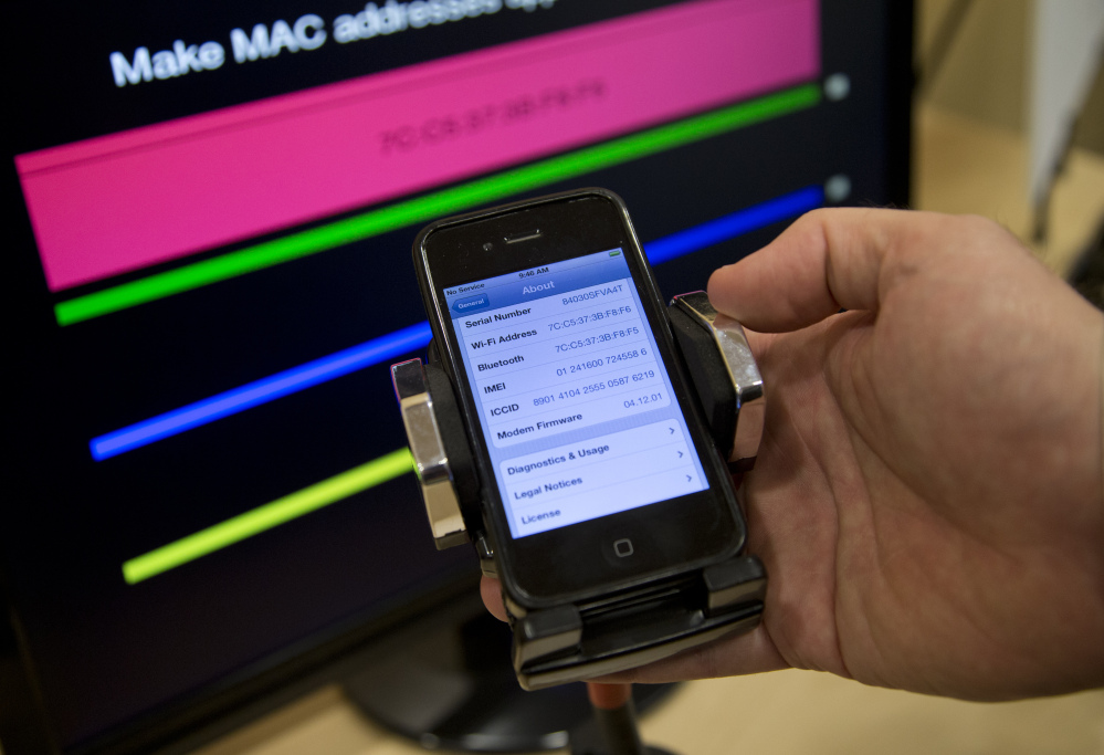 Technologist Seth Schoen holds a cellphone as it displays information, also seen on the screen behind, during a Federal Trade Commission mobile tracking demonstration Wednesday in Washington.