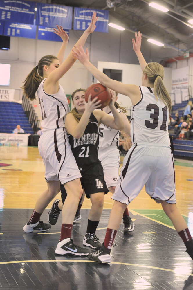 Taylor Oliver of Lincoln Academy tries to find an opening between Greely’s Ashley Storey, left, and Madison Cyr during their Western Class B girls’ basketball quarterfinal Wednesday at the Portland Expo. Greely advanced with a 55-27 victory.