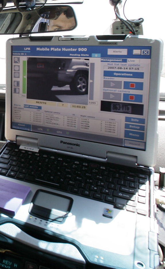 A dashboard computer in an Arizona police car reads and records license plates from passing cars.
