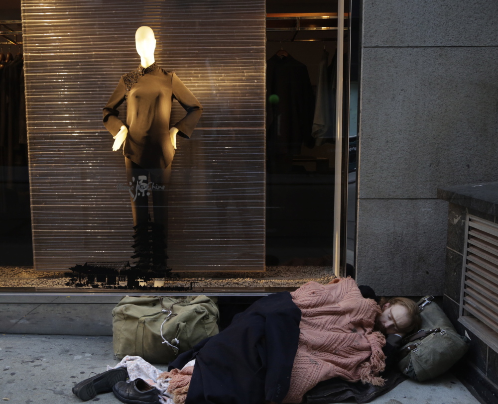 A destitute man sleeps under a holiday window at Blanc de Chine, an elegant clothing store in New York. A Brookings Institution study found that inequality increased across cities even though incomes often fell for wealthy households from 2007 to 2012.