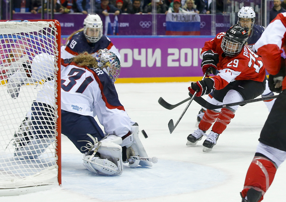 Marie-Philip Poulin of Canada (29) shoots to score the tying goal against USA goalkeeper Jessie Vetter (31) during the third period of the women’s gold medal ice hockey game Thursday.
