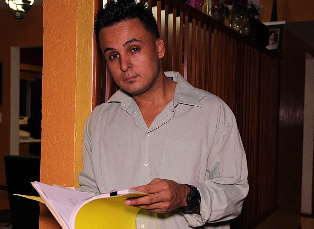 Carlos M. Gomez looks over documents in his Kendall, Fla., home Jan. 30. He was wrongfully arrested in 2011 and accused of laundering Wachovia bank costumers’ money through an account bearing his name. A bank employee had created the false account.