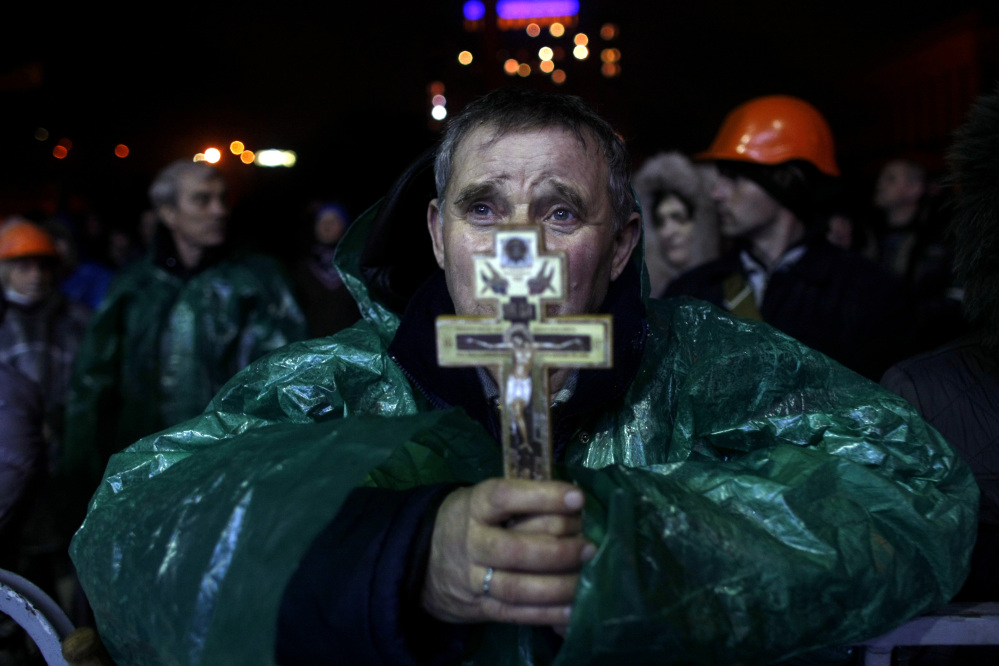 An anti-government protester holds a crucifix as he prays at Independence Square in Kiev, Ukraine, Thursday.