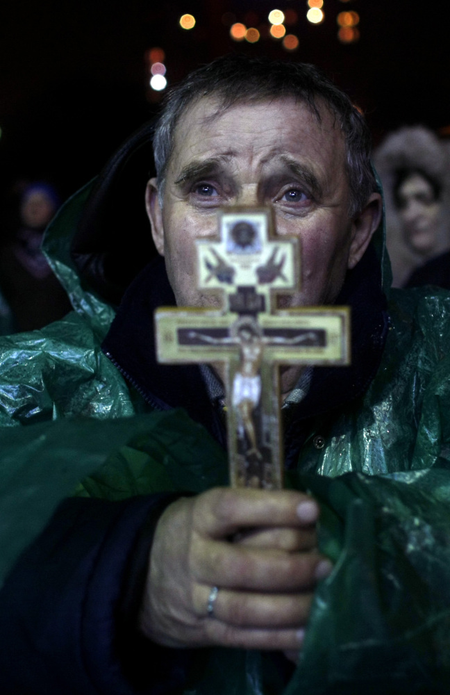 An anti-government protester holds a crucifix as he prays at Independence Square in Kiev, Ukraine, Thursday.