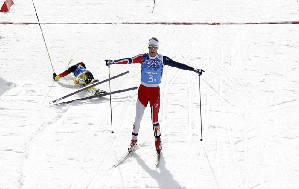 Norway’s Joergen Graabak celebrates winning the gold as Germany’s silver medal winner Fabian Riessle, left, falls into the snow after crossing the finish line of the cross-country portion of the Nordic combined Gundersen large hill team competition at the 2014 Winter Olympics, Thursday, Feb. 20, 2014, in Krasnaya Polyana, Russia.
