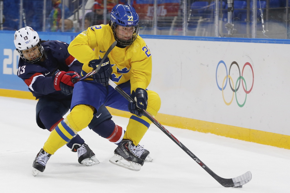 Emma Eliasson of Sweden takes control of th e puck away from Julie Chu of the United States during the first period of the 2014 Winter Olympics women’s semifinal ice hockey game. Chu has been selected to carry the American flag at the closing ceremonies.