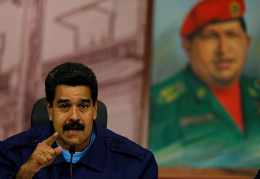 Venezuela’s President Nicolas Maduro speaks next to a painting of the late Hugo Chavez during a news conference in Caracas on Friday. A report accuses the government of using excessive and unlawful force against protesters repeatedly since Feb. 12 and of censoring the news media.