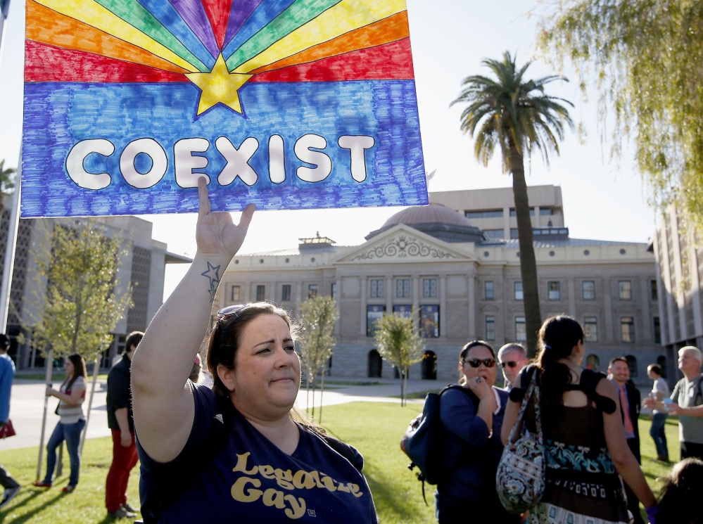 Jo Beaudry holds up a sign as she joins gay rights supporters protesting in Phoenix a bill that passed the Arizona Legislature that would allow businesses to refuse service to gays on religious grounds.