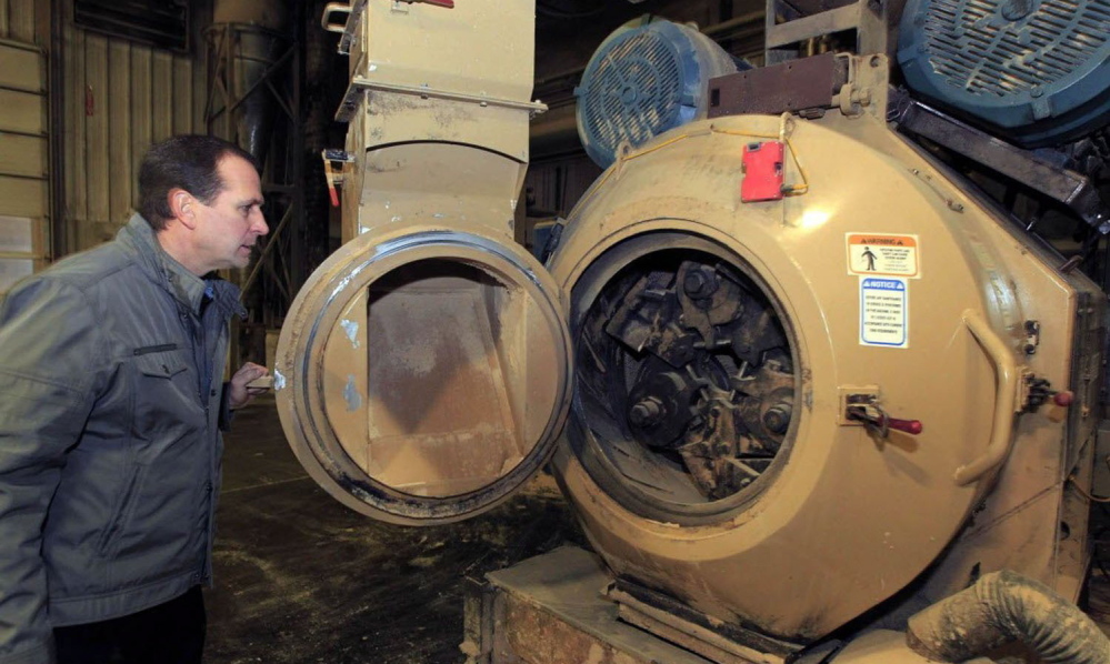 Larry Dejno shows a machine that grinds sawdust and wood shavings into pellets to be used in pellet stoves and furnaces at his Kenosha, Wis., plant. Dejno has seen an increase in sales of the pellets as prices rise on other home heating fuels.