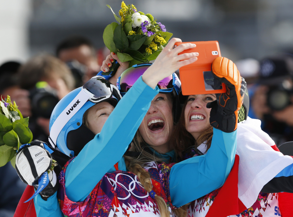 Women’s snowboard parallel slalom medalists, from left to right, bronze medalist Amelie Kober of Germany, silver medalist Anke Karstens of Germany center, and gold medalist Julia Dujmovits of Austria take photos of themselves during a flower ceremony at the Rosa Khutor Extreme Park at the 2014 Winter Olympics on Saturday in Krasnaya Polyana, Russia.