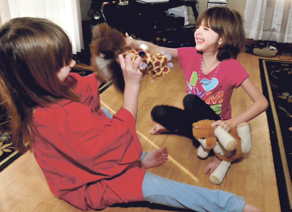 Kaitlyn Parker, right, and her sister Briana play with toys Wednesday at their home in Augusta. Kaitlyn is dealing with a medical condition known as Marfan syndrome, a genetic disorder that can affect ligaments and the heart.