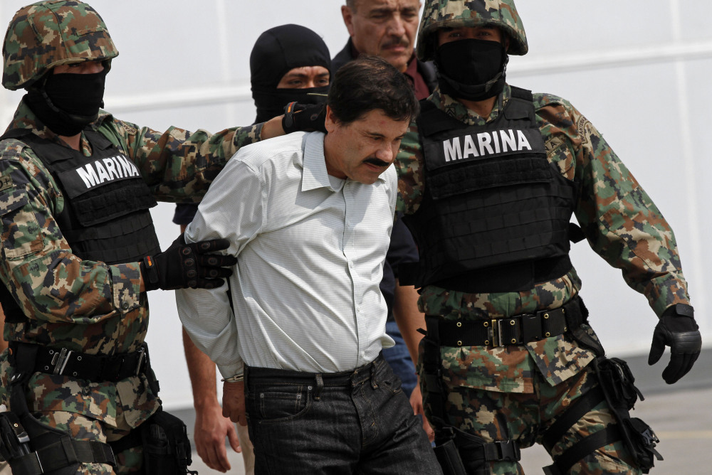 Joaquin “El Chapo” Guzman is escorted to a helicopter in handcuffs by Mexican navy marines at a navy hanger in Mexico City, Saturday.