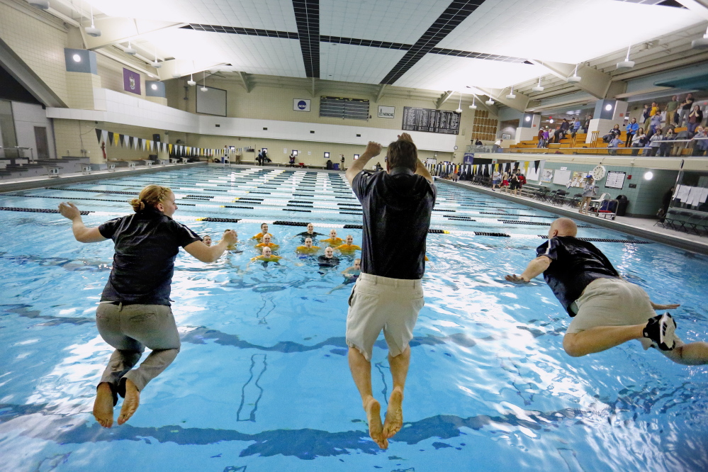 Greely assistant coaches Alisha Copp, left, and Doug Pride, center, and head coach Rob Hale jump into the pool at Bowdoin College in Brunswick Tuesday after the Rangers captured the state championship at the Class B boys’ swim meet.