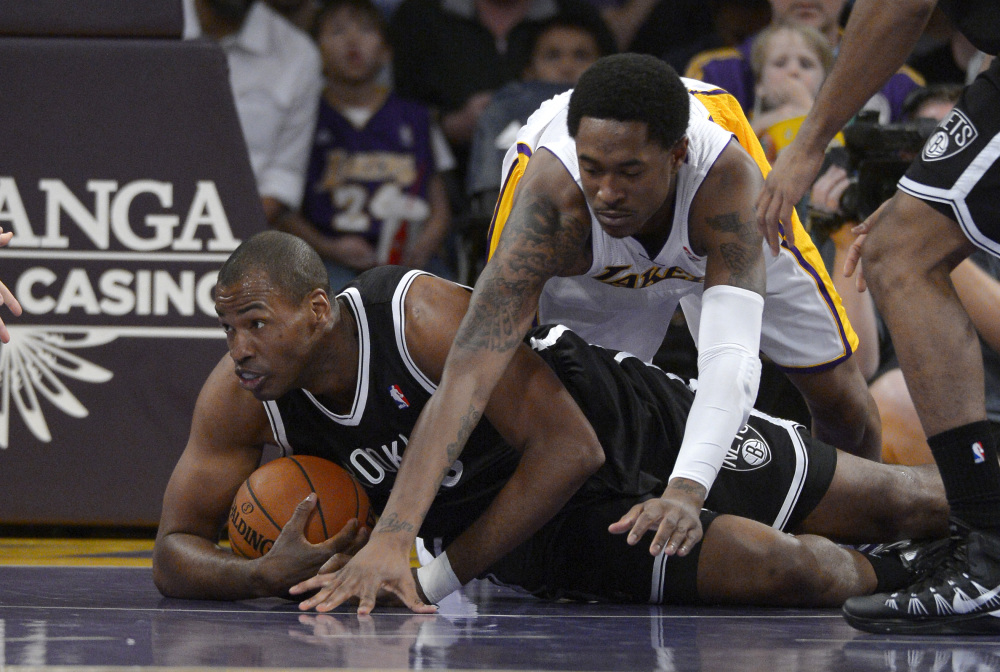 Brooklyn Nets center Jason Collins, left, battles for a loose ball with Los Angeles Lakers guard MarShon Brooks during the first half of an NBA basketball game Sunday in Los Angeles. Collins was making history by being the first openly gay NBA player on the court.