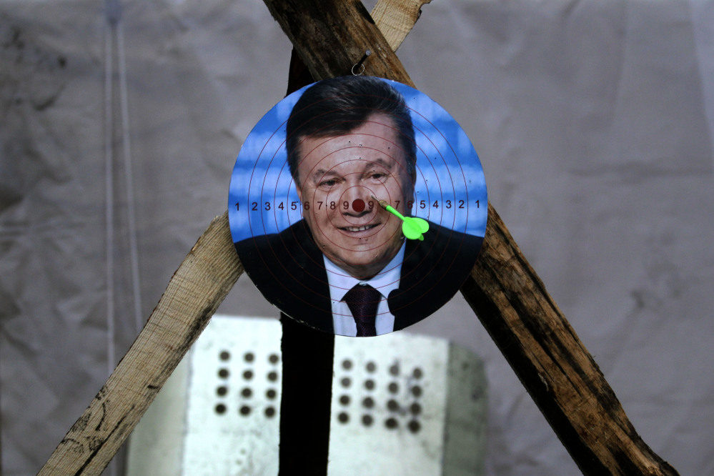 A portrait of Ukraine’s embattled president Viktor Yanukovych is used for a game of darts at Independence Square in Kiev, Ukraine, on Monday.