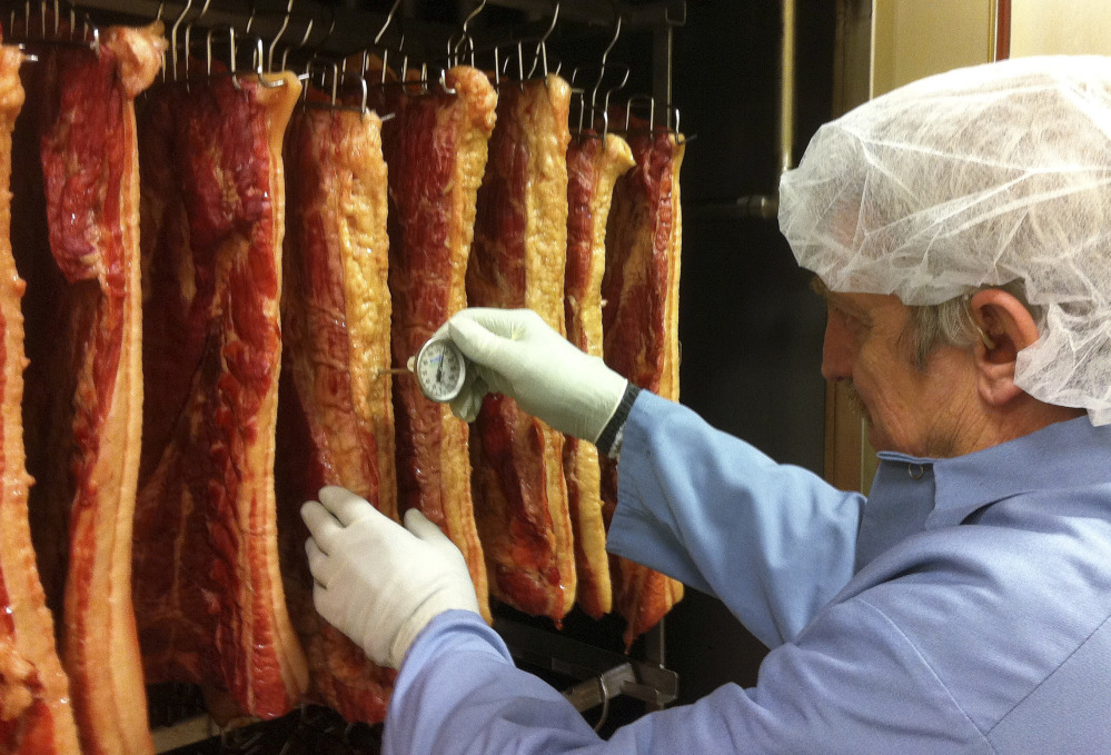 Don Jutras, Vermont Smoke and Cure's plant manager, measures the temperature of bacon hanging in the company’s smokehouse in Hinesburg, Vt. The company has more than quadrupled its workforce since 2006.