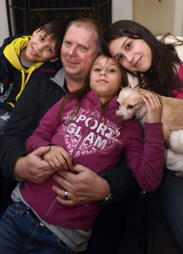 David Bundy sits with his newly adopted children, Max, 11, from left, Alla, 9, and Karina, 14. He headed home to Montgomery, Ala., early with the children to escape the violence.