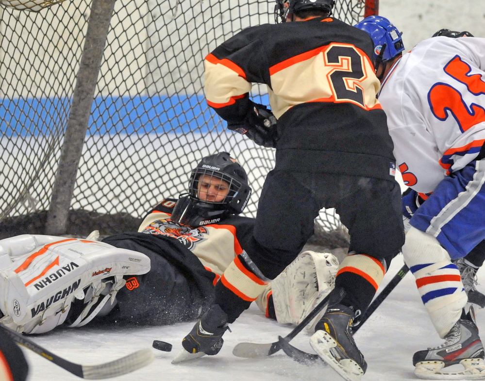 Brunswick goalie Blake Alexander keeps his eye on a loose puck as Brady Martin, right, of Lawrence/Skowhegan looks to get the rebound while being defended by Matt Brooks of Brunswick. Brooks scored in a 1-0 victory.