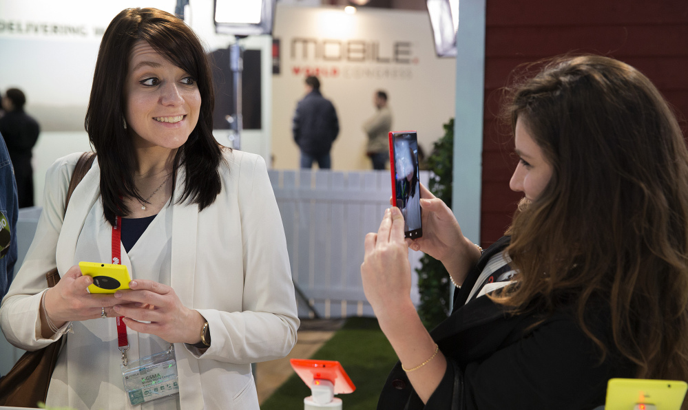 A woman takes a picture of her friend with a Nokia Lumia 1520 phone this week at the Mobile World Congress in Barcelona, Spain. Wireless companies at the show displayed smartphones with much-improved camera software.
