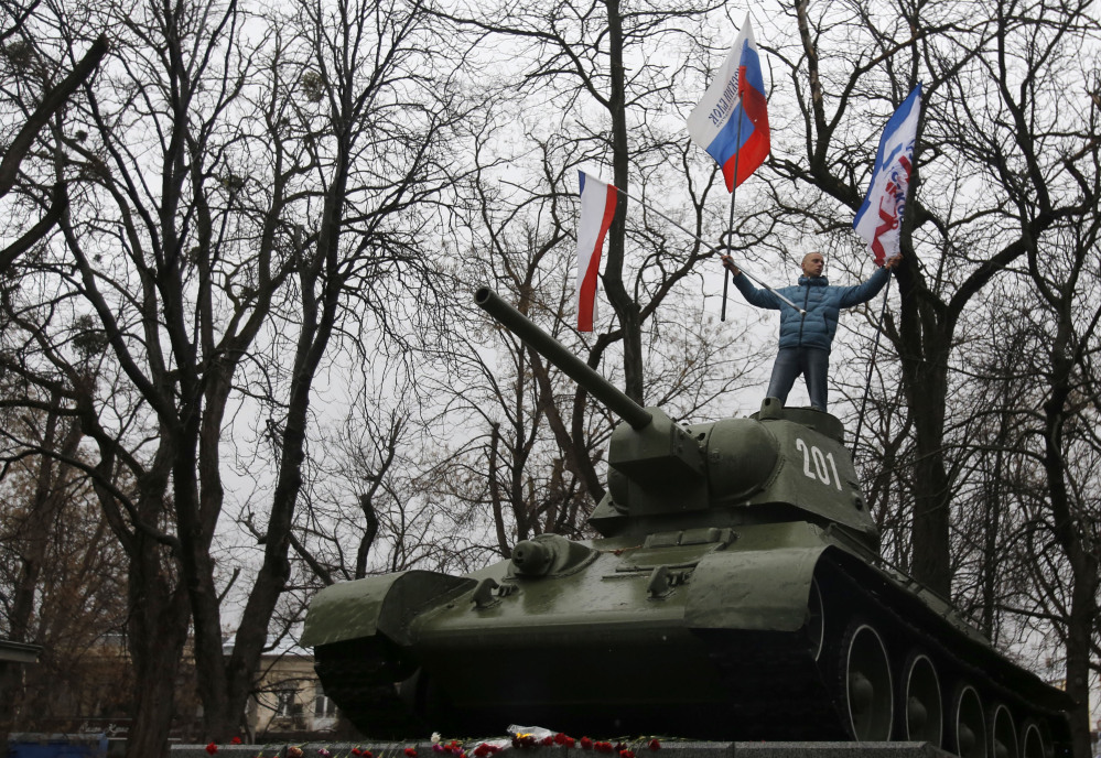 A Pro-Russian demonstrator waves Russian and Crimea flags from an old Soviet Army tank during a protest in front of a local government building in Simferopol, Crimea, Ukraine, on Thursday. Ukraine’s acting interior minister said dozens of men seized local government and legislature buildings in the Crimea region.