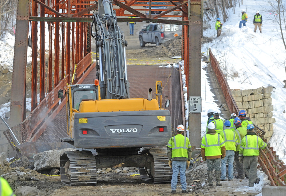 Crews stand by as an excavator equipped with a jackhammer works on the New Sharon bridge Thursday.