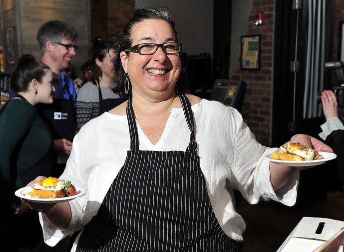 PORTLAND - FEBRUARY 28: Lisa Kostopoulos, owner of the Good Table Restaurant in Cape Elizabeth, winner for the past four years, but second place this year, walks off with two servings of the first place winning creation from Eve's, Portland Harbor Hotel, Pork Belly Waffle with egg, sunny side up, as people enjoy great breakfast food created by area restaurant chefs at the Incredible Breakfast Cook-Off at Sea Dog Brewing in South Portland Friday, February 28, 2014. (Photo by Gordon Chibroski/ Staff Photographer)