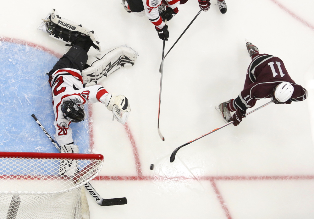 Aidan Black of Greely tries to slip the puck past Zachary Hand of Camden Hills, Friday, Feb. 28, 2014, during the 2nd period of the Class B West semifinal game at the Colisee in Lewiston.