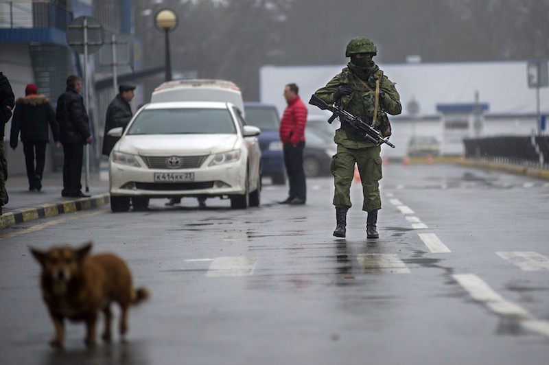 An unidentified armed man patrols a square in front of the airport in Simferopol, Ukraine, Friday, Feb. 28, 2014. Russian military were blocking the airport in the Black Sea port of Sevastopol in Crimea near the Russian naval base while unidentified men were patrolling another airport serving the regional capital, Ukraine's new Interior Minister Arsen Avakov said on Friday.