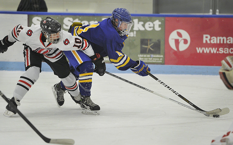 Falmouth's Tyler Jordan, No. 4, tries to move the puck around the defense of Scarborough's Cam Nigro, No. 10, in this Dec. 9, 2013, game played at the at the University of New England.