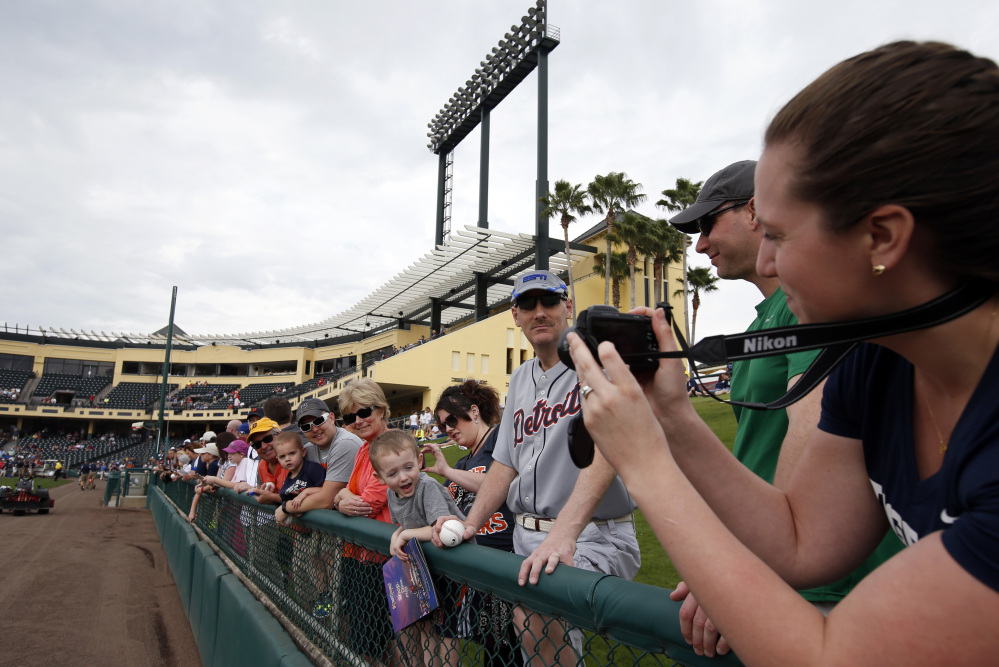 Emily Frederick, right, takes a picture of husband Brendt Frederick, wearing white-rimmed sunglasses, and son Parker Frederick, 2, before a spring training baseball game in Kissimmee, Fla., on Wednesday. After a long, cold winter, Americans across the winter-weary Midwest and the East Coast are desperate to escape.