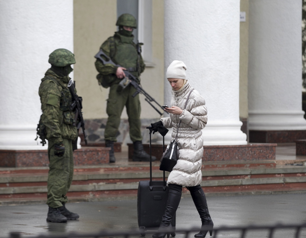 A woman walks past armed men at the Simferopol airport in the Crimea region on Friday. Armed men took control of two airports in the Crimea region, raising tensions with the West.