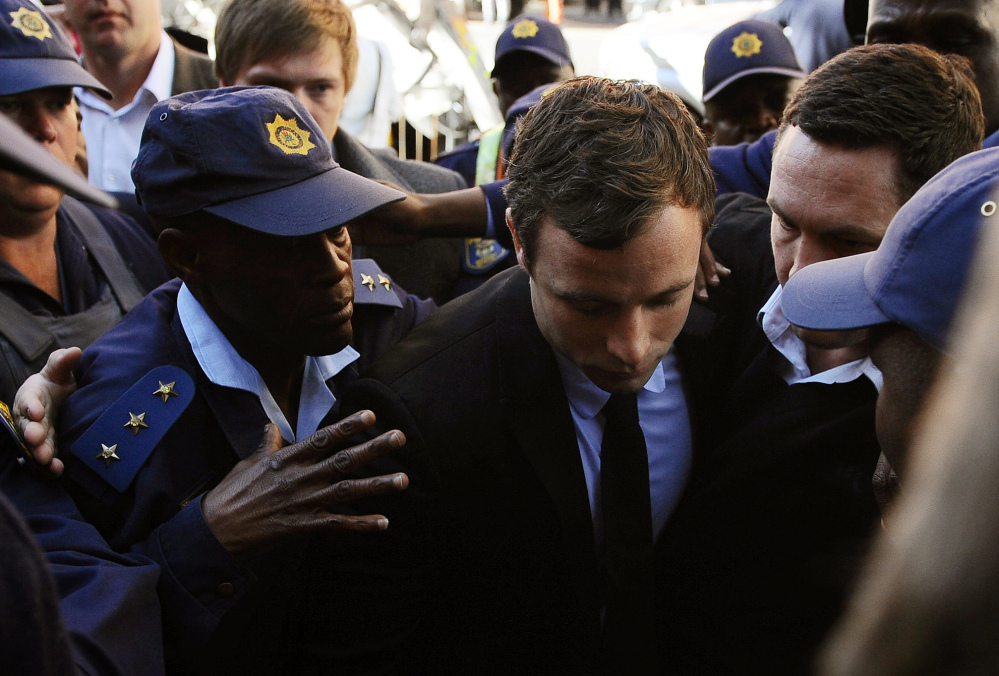Oscar Pistorius, center, arrives outside the magistrates court in Pretoria, South Africa, in August 2013 where he was indicted on charges of murder and illegal possession of ammunition for the shooting death of his girlfriend Reeva Steenkamp. Pistorius goes on trial on Monday.