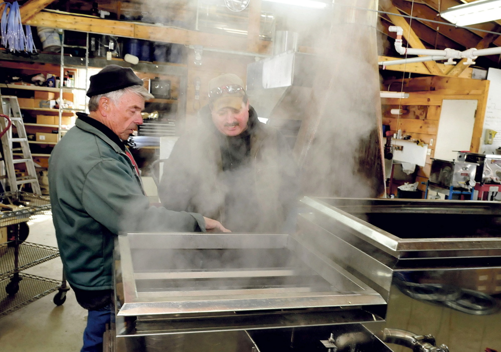 Bob Bacon, left, of the Bacon Farm in Sidney, speaks with Jim Wright of the Apple Ridge maple syrup operation in Cornville as steam rises from a sap evaporator in Sidney on Monday. Bacon said it was the second time he boiled syrup this season and expects his operation to increase this weekend as temperatures rise.