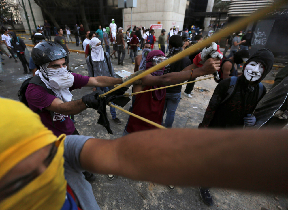 Demonstrators use a giant slingshot to launch stones at Bolivarian National Police during clashes in Caracas, Venezuela, Monday. Venezuelan opposition leader Henrique Capriles called for citizens to begin organizing committees that could sustain the pressure that continuing street protests have placed on the government of President Nicolas Maduro.