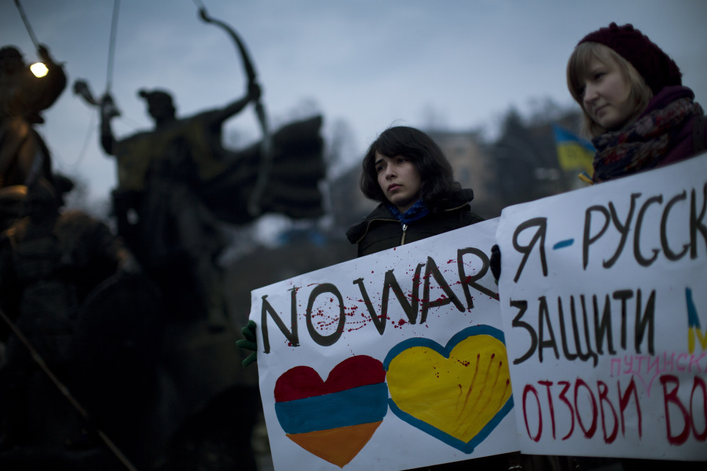 Ukrainians Maria, 23, right, and Vanui, 22, hold posters against Russia’s military intervention in Crimea, in Kiev, Ukraine, on Sunday. The poster on the right side reads in Ukrainian: “I am from Russia, please protect me and remove the weapons and soldiers from Ukraine.”