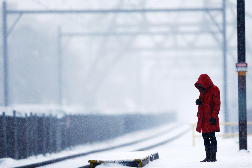 A morning commuter waits on a train during a winter snowstorm Monday, March 3, 2014, in Philadelphia.