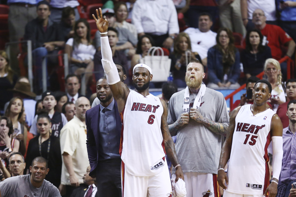Miami Heat players Dwyane Wade, left, LeBron James (6), Chris Andersen and Mario Chalmers (15) watch the end of an NBA basketball game in Miami, Monday, March 3, 2014 against the Charlotte Bobcats. LeBron James scored a team recond of 61 points. The Heat won 124-107.