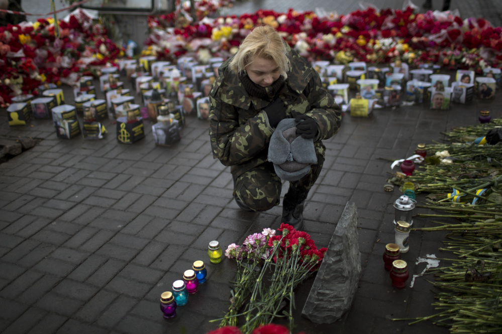 An Ukrainian woman wearing camouflage uniform pays respect at the site were her friend Ustim Golodniuk was killed in clashes with the police at the Shrine of the Fallen in Kiev’s Independence Square, Ukraine, Wednesday, March 5, 2014. The Shrine of the Fallen, located on Institutska Street, honors the fallen “Heroes” of the “Heavenly Sotnya” (Hundred). Over the course of the Euro Maidan protests, almost 100 protesters were killed by police.