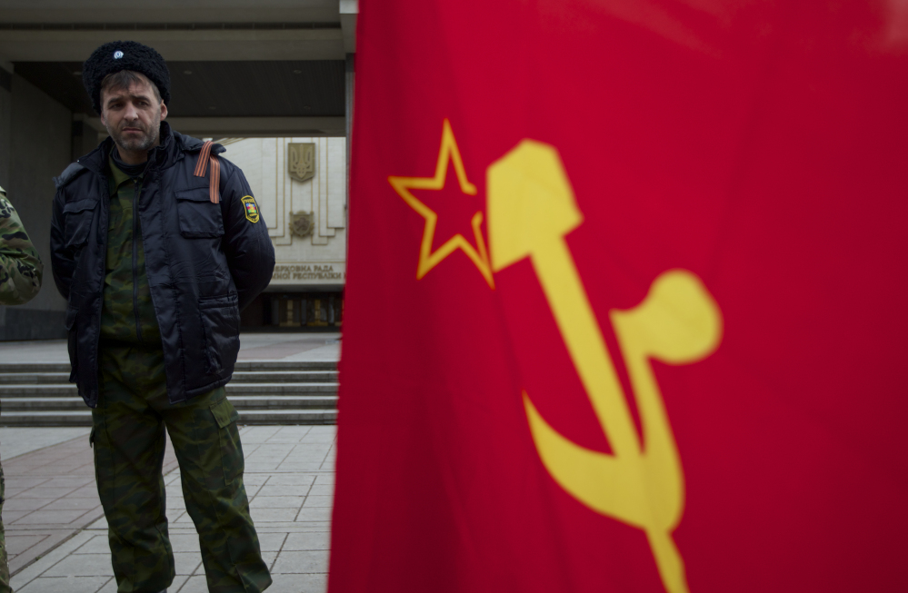 The hammer and sickle are seen on the Soviet flag as members of Cossack militia guard the local parliament building in Simferopol, Ukraine, on Thursday, March 6, 2014. Lawmakers in Crimea declared their intention Thursday to split from Ukraine and join Russia instead, and scheduled a referendum in 10 days for voters to decide the fate of the disputed peninsula. Russia’s parliament, clearly savoring the action, introduced a bill intended to make this happen.