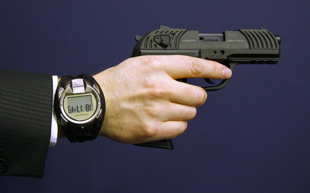 A man holding a prototype of a smart gun by Armatix also wears the gun’s security watch.