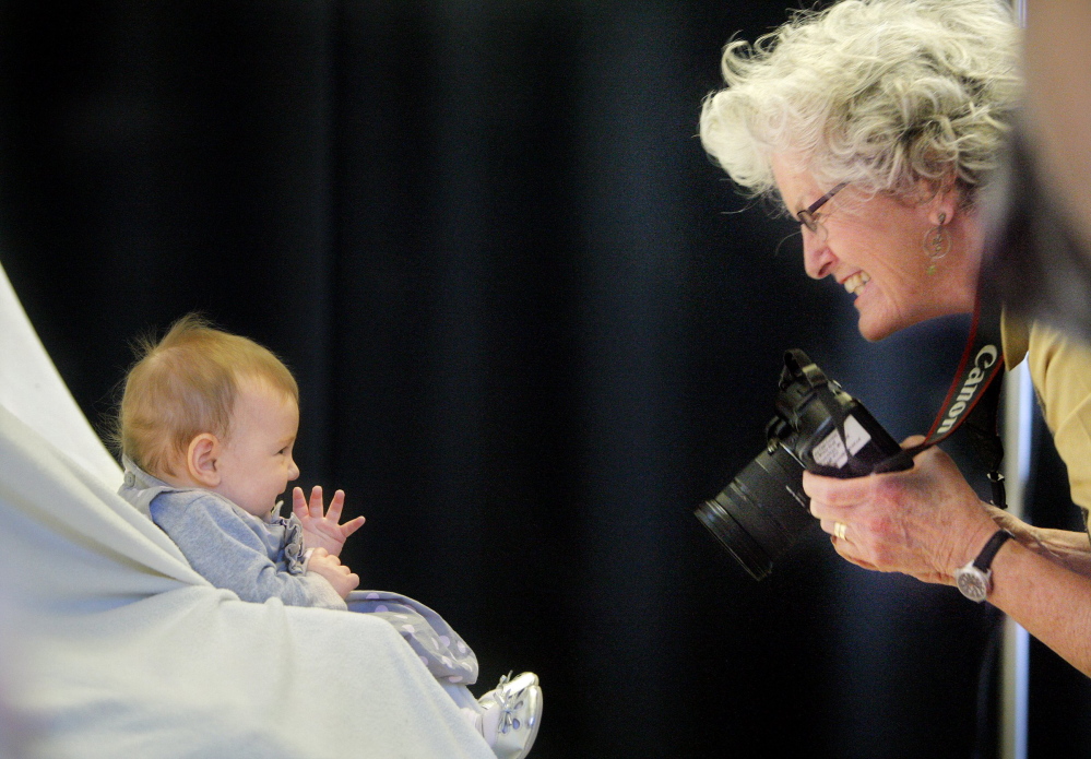 Photographer Jane Page-Conway gets a smile from 4-month-old Eva Dae Michaels of Falmouth during a 2012 casting call in Portland for announcements promoting the Harold Alfond College Challenge. The Harold Alfond Foundation will now automatically award a $500 Alfond college grant to all Maine babies, instead of making the college savings accounts an option.